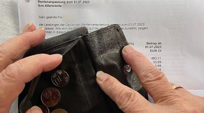 Zusehen ist eine ältere Hand die einen Geldbeutel hält mit nur ein paar Cent enthalten. Darunter ist eine Rentenabrechnung abgelegt.