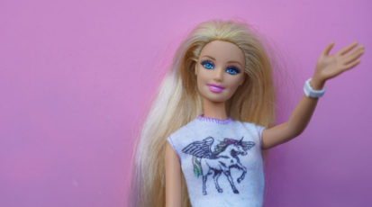 Eine blonde Barbie vor einem pinken Hintergrund.