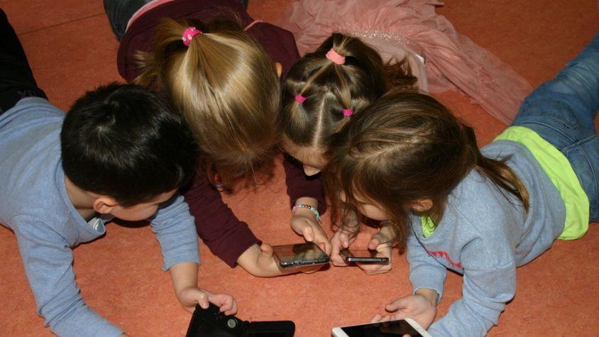 Vier Kinder schauen im Kreis auf Smartphones.