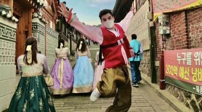 Henrik springt im koreanischen Hanbok in die Höhe, während Frauen hinter ihm ebenfalls traditionell koreanisch gekleidet sind.