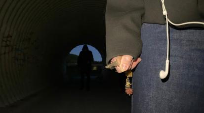 Eine Frau hält einen Schlüssel in der Hand. Hinter ihr ist eine dunkle Gestalt zu sehen.