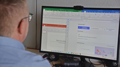 Ein Mann sitzt am Schreibtisch und schaut seinen Computerbildschirm.