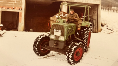 Glücklicher Mann auf einem alten Traktor im Schnee