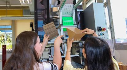 Zwei Studentinnen mit Prototypen aus Karton an der Dosier-Maschine