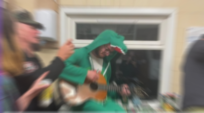 Ein Mann im grünen Nessiekostüm spielt Gitarre