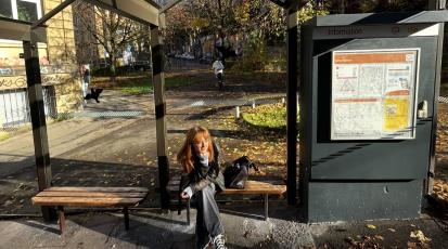 Frau sitzt an Bushaltestelle und wartet