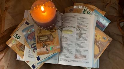 Eine Bibel mit Geld und Kerzen