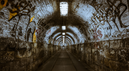 Ein langer dunkler Tunnel, mit Graffiti bemalt