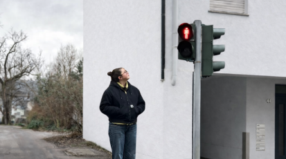 Frau an roter Ampel überlegt, ob sie schnell über die Straße gehen soll.