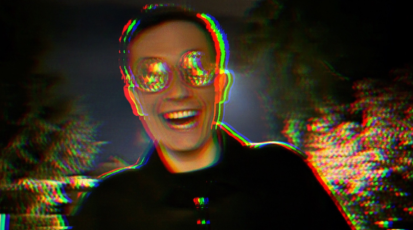 Eine männliche Person mit bunter Brille lacht verrückt in die Kamera. Die Umrisse sind etwas verzerrt