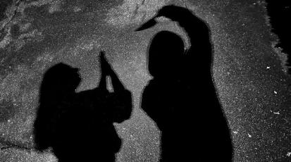 Schattenbild: Ein Mann bedroht eine Frau mit einem Messer.