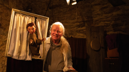 Der Puppenspieler Veit Utz Bross ist mit einer Handpuppe auf seiner Theaterbühne.