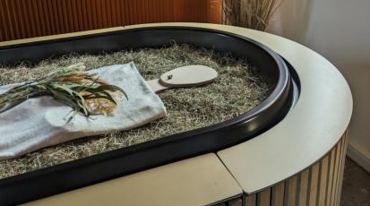 Eine Holzfigur liegt in einem sargähnlichen Behältnis, dem Kokon.