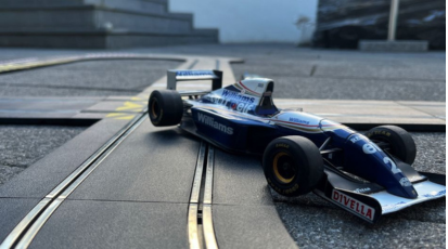 Formel 1 Spielzeugauto fährt abseits einer Carrerabahn-Strecke.