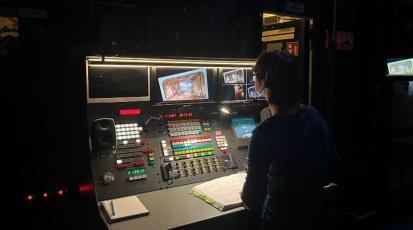 Inspizientin ist über Arbeitspult gebeugt.