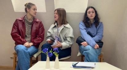 Drei Frauen sitzen im Wartezimmer. Zwei davon tuscheln.