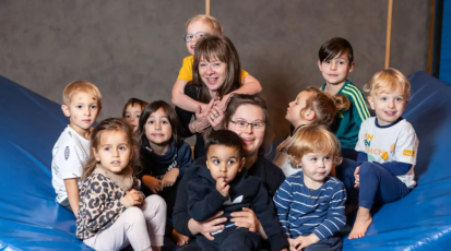 Annette sitzt umgeben von gesunden und beeinträchtigten Kindern auf einer Sportmatte