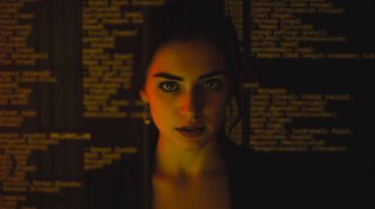 Frau, die zentral im Bild steht und geradeaus schaut. Im Hintergrund ist Code zu sehen.