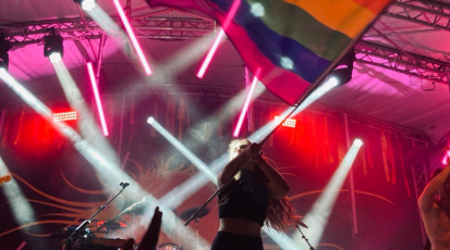 Produzentin steht mit LGBTQ-Flagge auf Bühne