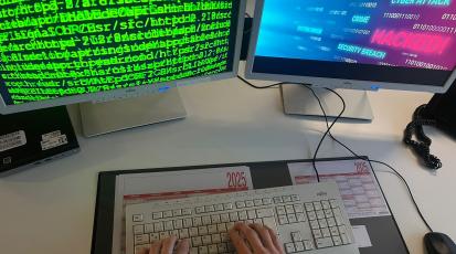 Hacker vor zwei Bildschirmen.