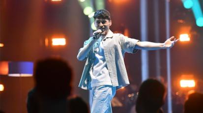 Vincent Varus beim ESC-Vorentscheid: Er ist in der Mitte des Bildes auf der Bühne, schaut beim singen frontal in Richtung Kamera. Im Vordergrund ist das Publikum zu sehen.