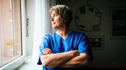 Hebamme schaut aus Fenster.