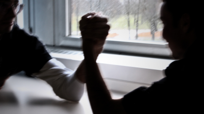 Zwei Männersilhouetten machen Armdrücken