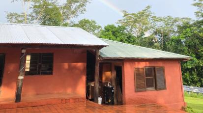 Man sieht eine paraguayische Küche, die "cocinita" von außen. Über ihr erscheint ein Regenbogen am Himmel. 