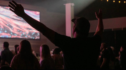 Ein Mann hebt seine Hände in die Höhe während er Kirchenlieder singt. 