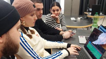 Die vier Student*innen sitzen konzentriert vor dem Laptop und schneiden ihren Dokumentarfilm.