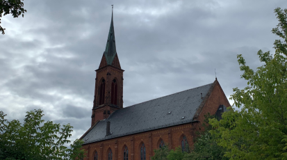 Foto einer Kirche mit Bäumen an beiden Seiten des Gebäudes