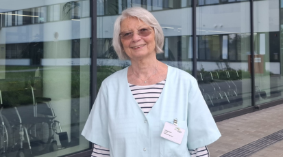 Die Grüne Dame lächelnd vor dem Krankenhaus.