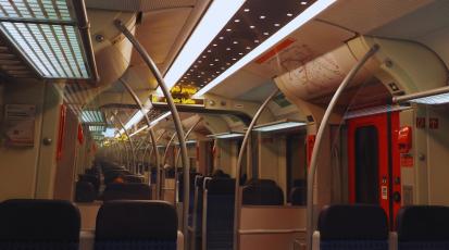 Auf dem Bild ist eine S-Bahn von innen zu sehen. Man sieht eher die Decke der S-Bahn und Sitzplätze, die zum Teil mit Menschen belegt sind.