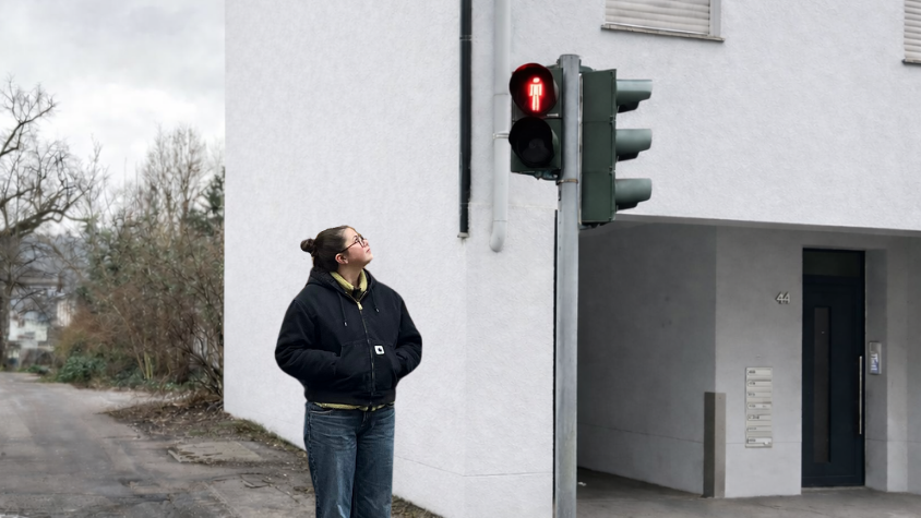 Frau an roter Ampel überlegt, ob sie schnell über die Straße gehen soll.