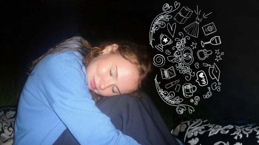 Frau sitzt im Dunkeln. Die Beine sind an den Körper herangezogen und der Kopf auf den Knien abgelegt.