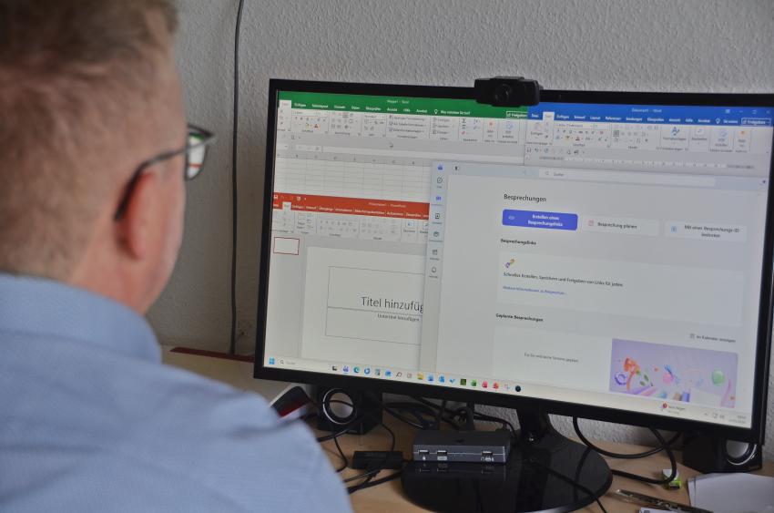 Ein Mann sitzt am Schreibtisch und schaut seinen Computerbildschirm.