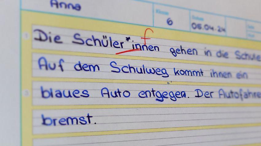 Diktatheft, in welches mehrere Sätze geschrieben sind. Das Wort Schüler*innen ist als Fehler angestrichen. 