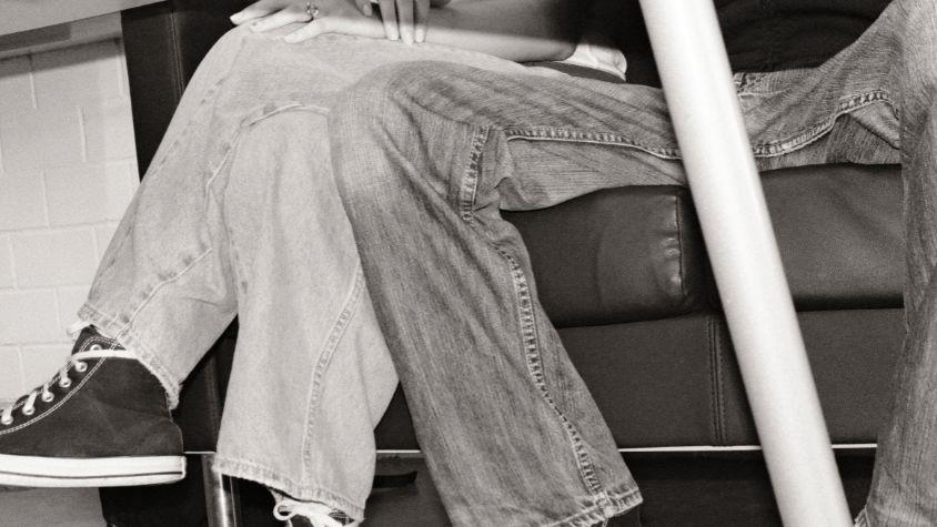 Ein Mann sitzt sehr breitbeinig in der Bahn und nimmt einer Frau den Platz weg