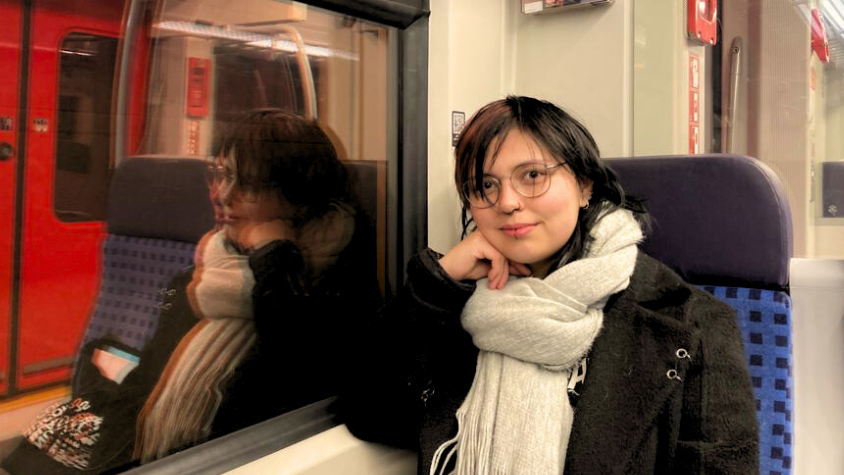 Ellen Pfeiffer (22) sitzt in der S-Bahn und lacht in die Kamera. 