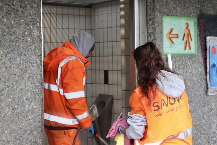 Die Reinigungskräfte bei der Arbeit mit Schlauch und Lappen in der Hand. 