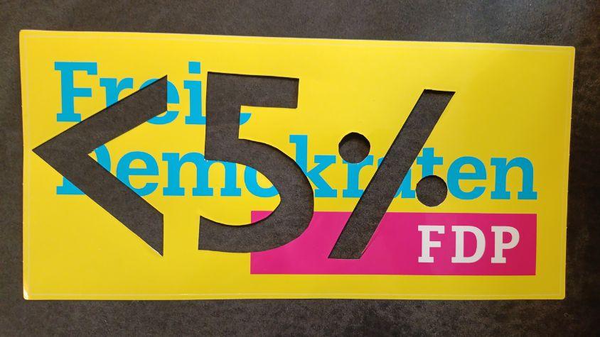 Auf dem Bild sieht man ein Sticker der FDP, in welchen <5% eingeschnitten ist.