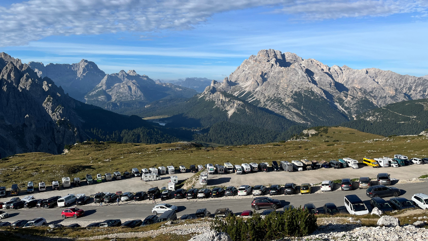 Viele parkende Autos, im Hintergrund ein Bergkamm.