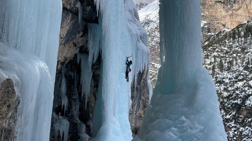 Eine Frau klettert an einer Eiswand hoch.