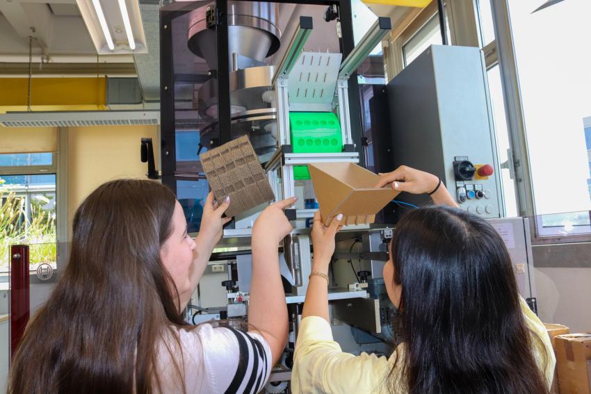 Zwei Studentinnen mit Prototypen aus Karton an der Maschine