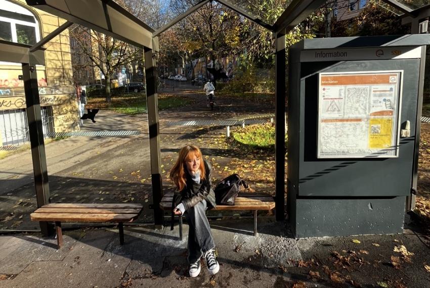 Frau sitzt an Bushaltestelle und wartet