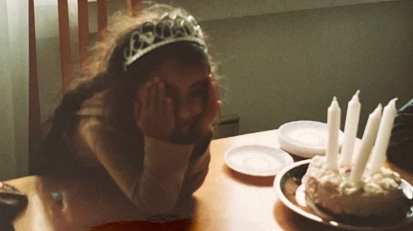 Ein kleines Mädchen an ihrem Geburtstag, voller Vorfreude vor Ihrer Torte am Tisch.