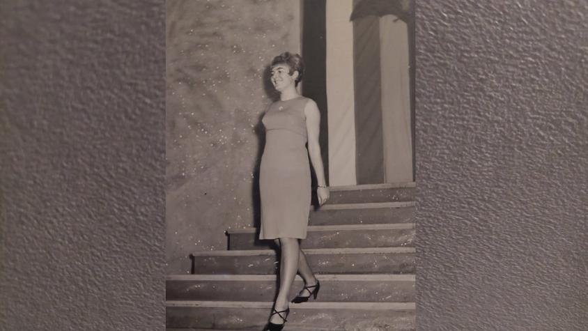 Meine Oma trägt ein Kleid und hohe Schuhe. Sie läuft eine Treppe hinunter und lacht.