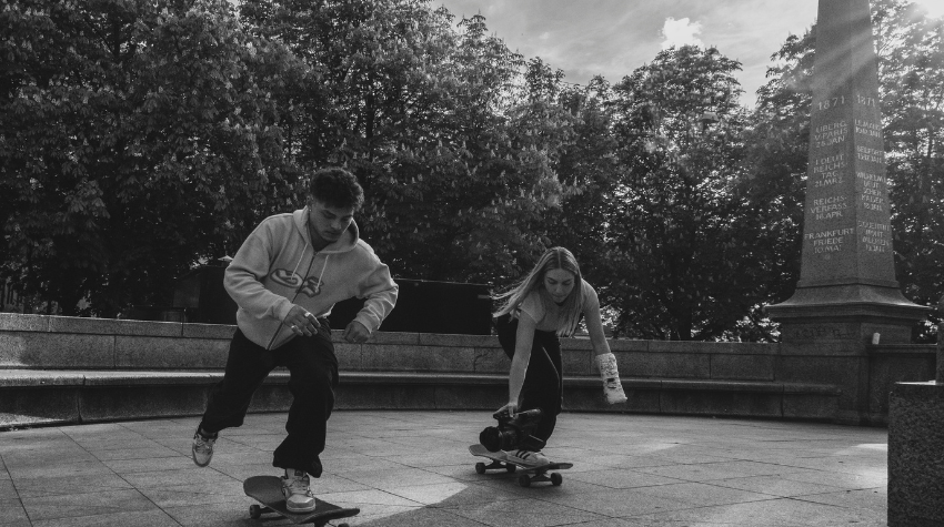 Eine Filmerin fährt neben einem Skater her und filmt dabei