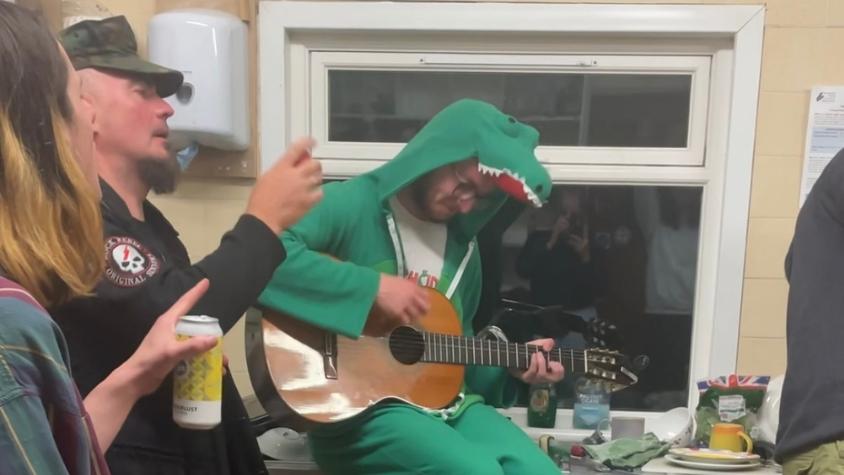 Ein Mann im grünen Nessiekostüm spielt Gitarre