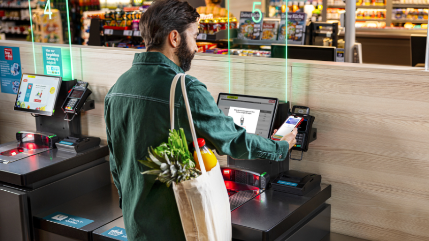 Ein Mann bezahlt an einer Selbstbedienungskasse. 
